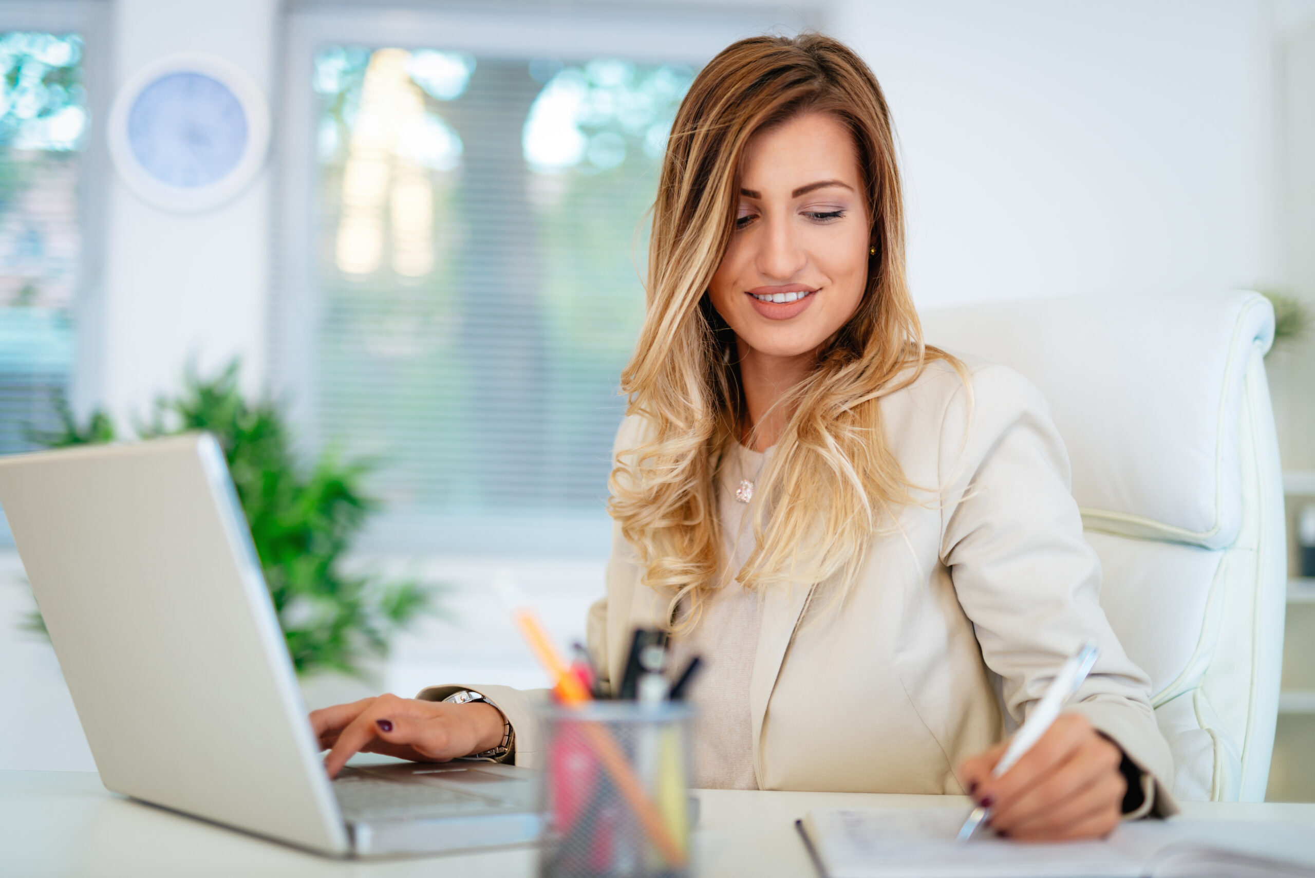 Business woman working online with a laptop and notebook in office checking the business plan.